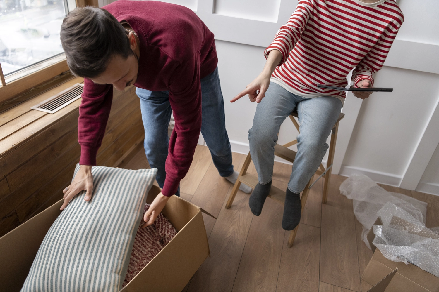 Roland Renner GmbH - Immobilienverwaltung und Gebäudedienstleistungen - Zwei Personen packen Haushaltswaren in einem hellen Raum aus.